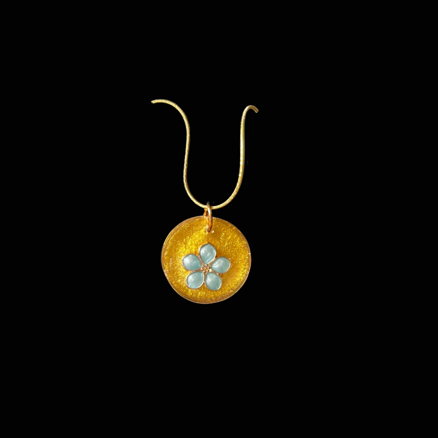 Blå skönhet - ett handgjort halsband med skimrande guldton och mjuk blå blomma. Ett smycke som fångar sommarens värme och lugn.