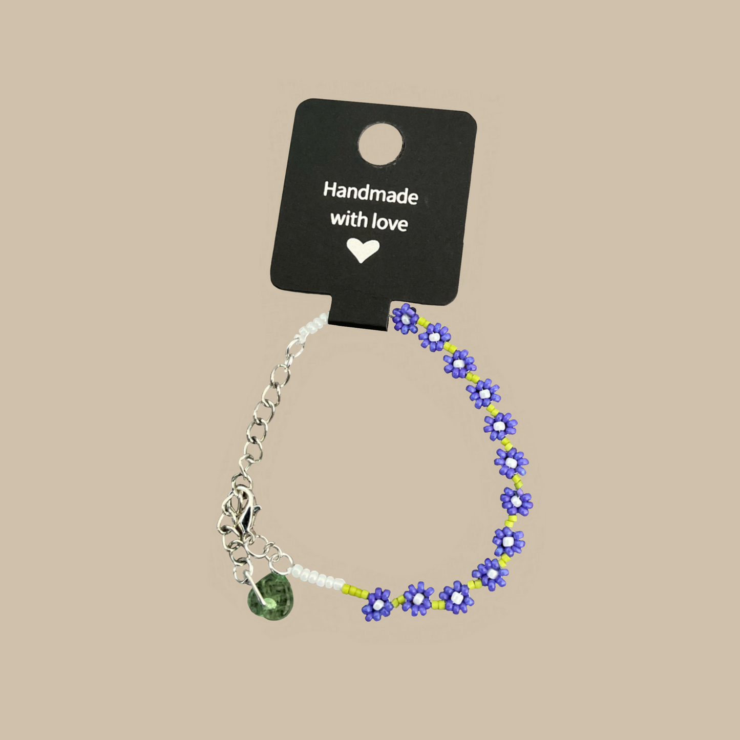 Handgjort armband med små lila blommor och gröna detaljer. Ett lekfullt och unikt smycke inspirerat av sommarens blommor.