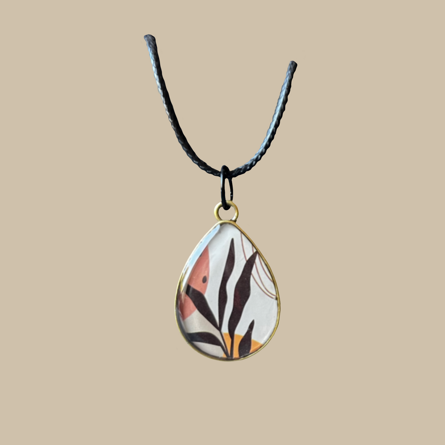 Unikt handgjort halsband i droppform med grafiskt naturinspirerat motiv i varma toner. Ett elegant och konstnärligt statement-smycke.
