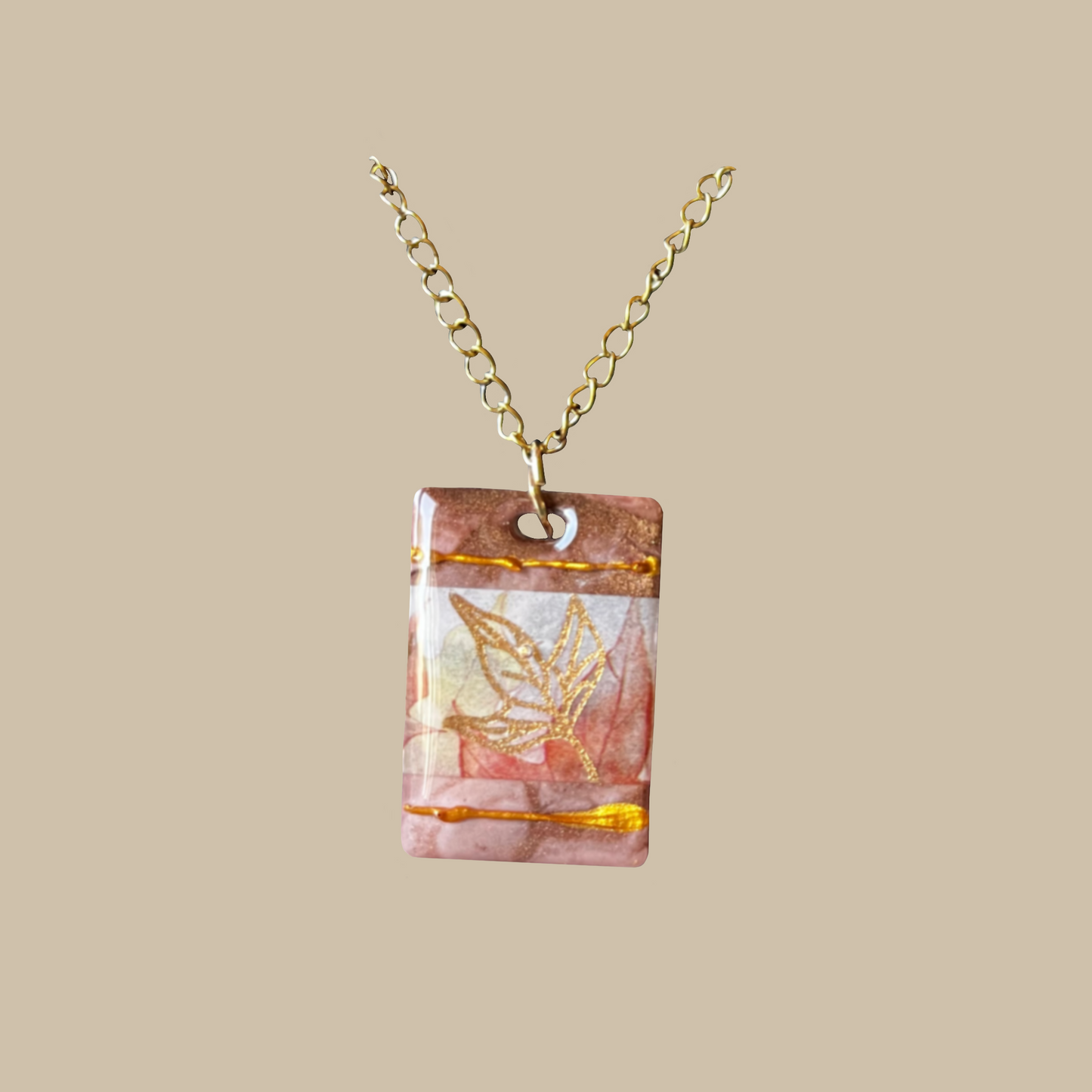 Handgjort halsband i mjuka rosa toner med gyllene detaljer och bladmotiv. Unikt smycke från kollektionen Aurea.