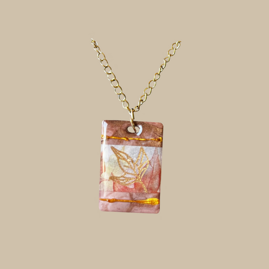 Handgjort halsband i mjuka rosa toner med gyllene detaljer och bladmotiv. Unikt smycke från kollektionen Aurea.