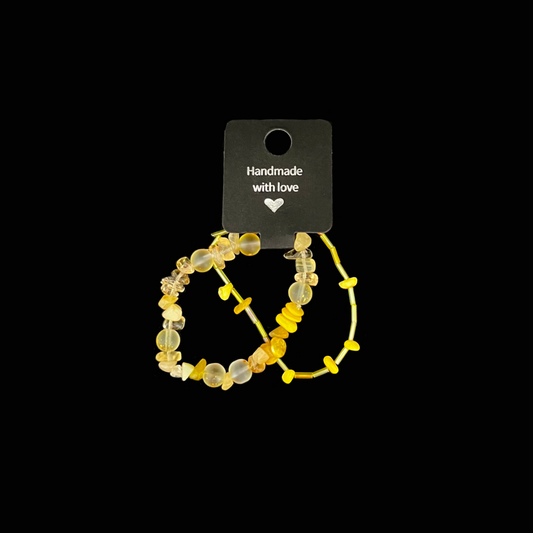 Lys upp din stil med dessa två handgjorda armband i glada gula nyanser och skimrande pärldetaljer.