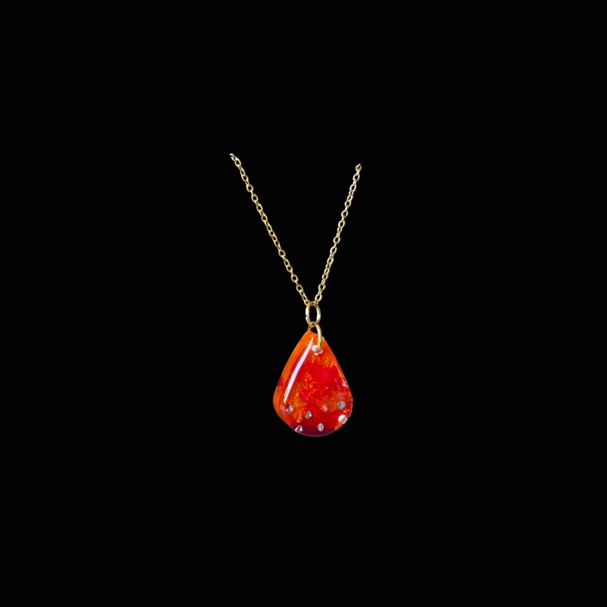 Handgjort droppformat halsband i resin med röd-orange glitter. Stilrent och färgstarkt smycke – unikt och tidlöst.