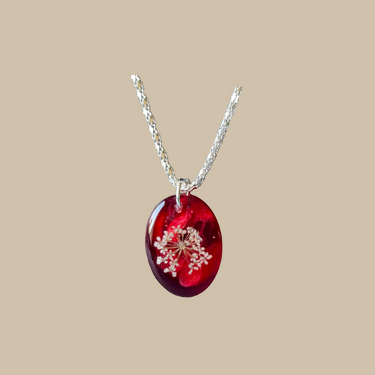 Unikt handgjort halsband med små vita blomdetaljer i djupa röda toner. Ett romantiskt och konstnärligt smycke med poetisk känsla.