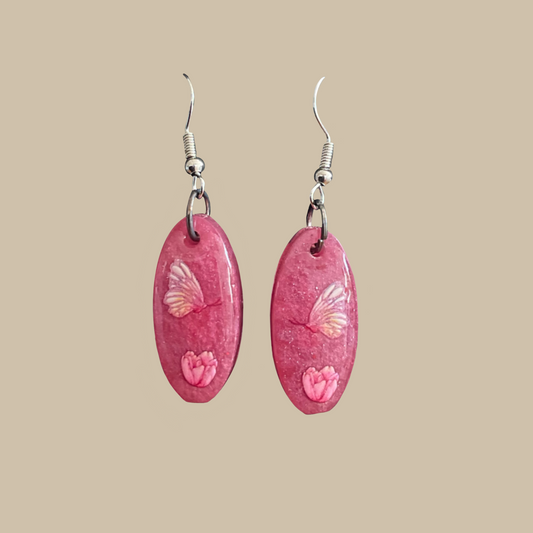 Unika handgjorda örhängen i rosa med fjärils- och blomdetaljer. Perfekta för en romantisk och mjuk stil.