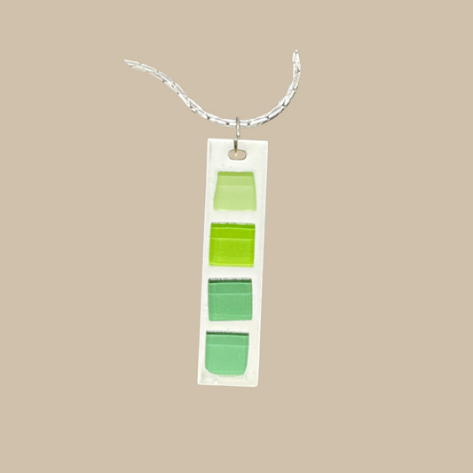 Limea är ett handgjort halsband i harts med grön glasmosaik. Grafiska och  modern minimalistisk design. Ett unikt statement-smycke från kollektionen Nordica