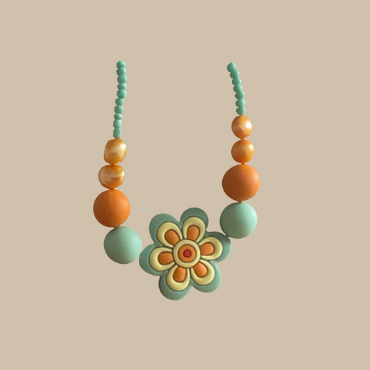 Lekfullt handgjort halsband med blomma i mint och aprikos. Ett färgstarkt smycke med retroinspirerad känsla.
