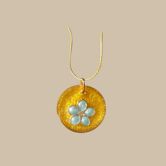 Unikt handgjort halsband med skimrande guldfärg och blomdetalj i ljusblå toner. Ett feminint och elegant smycke i ett enda exemplar.