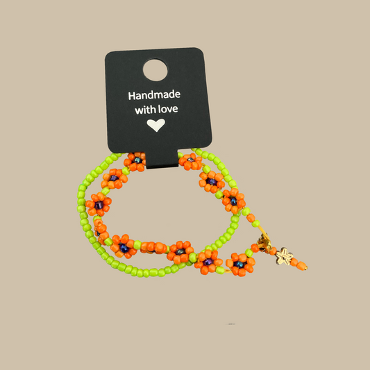 Lekfullt handgjort armband med små blommor i orange och grönt. Ett unikt smycke fyllt av sommar och färg.